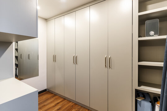 Contemporary Built-in Wardrobe Closet with Light Beige Doors, Gold Handles, and Open Shelving in a Dressing Room