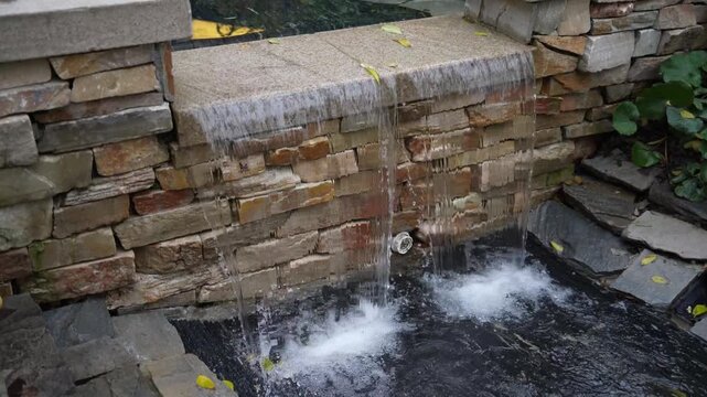 A small artificial waterfall with a stone wall
