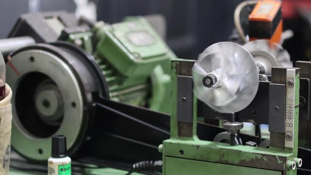 Turbocharger balancing machine in operation. Dynamic balancing of metal turbine wheel and impeller shaft on industrial precision equipment. Professional turbo repair service.