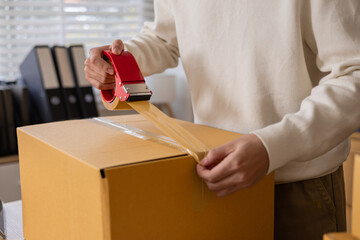 Small business owner working in home warehouse scene, worker apply shipping label on parcel and...