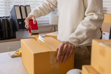 Small business owner working in home warehouse scene, worker apply shipping label on parcel and...