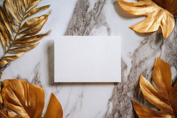 Textured card surrounded by gold foliage on a marble surface, top view