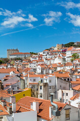 Scenic vertical view of dense residential houses with orange tiled roofs and white facades in the historic center of Lisbon, Portugal.
