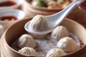 Close-up of a perfectly pleated Xiao Long Bao soup dumpling lifted from a steaming bamboo basket.
