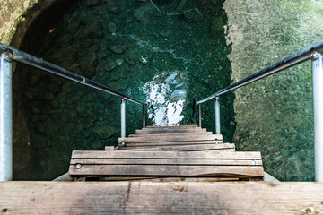 Downward Perspective of Wooden Steps and Metal Railings Leading into a Pool of Deep, Emerald Green Canyon Water