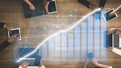 A dynamic scene of business professionals using tablets and laptops to analyze growth data. Charts and graphs illustrate trends in a modern office setting. Copula