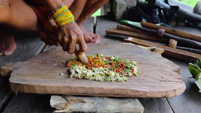 Mentawai shaman in the traditional attire and body decorations preparing the poison for hunting in his hoise in Siberut island West Sumatra Indonesia