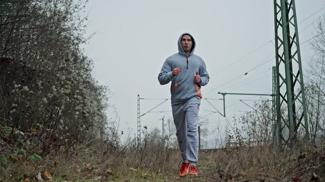 Runner Advances Across Scenic Landscape, Focused Runner Moves Forward Across Diverse Natural Surroundings Smoothly, Athlete Maintains Steady Pace As They Traverse Lush Fields Beneath Cloudy Sky