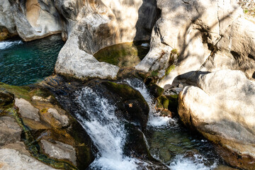 Downward Close-Up of Fast-Flowing Water Cascading Over Mossy, Water-Eroded Rocks into Natural Canyon Basins