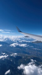 Fototapeta premium Airplane Wing Against Clear Blue Sky Over Clouds and Mountains in Bright Daylight