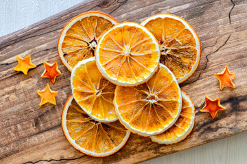 Heap of dried orange slices and dried orange peel stars on wooden background. Orange chips. Top view