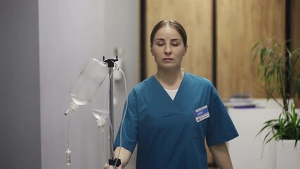 Nurse delivering IV drip to patient room while walking hospital corridor