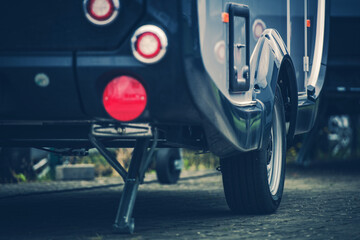 Close View of a Travel Trailer Wheel and Hitch in a Parking Area on a Cloudy Day