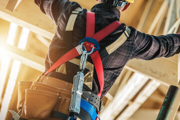 Worker With Safety Harness Performs Task at Construction Site in Daylight