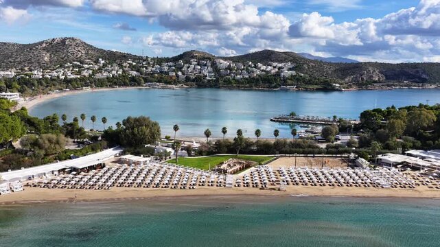 Aerial drone cinematic video of amazing organized sandy celebrity beach of Asteras featuring Temple of Apollo Zoster a true ancient cultural heritage, Vouliagmeni, Athens riviera, Greece