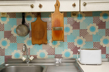 Kitchen with a sink, utensils, and colorful wall tiles during daylight