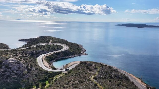 Aerial drone cinematic video of serpent seaside road forming small coves known as "Limanakia" next to famous Asteras Peninsula and lake Vouliagmenis, Athens Riviera, Attica, Greece