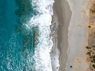 Direct Overhead Drone Shot Highlighting the Contrast Between the Deep Blue Sea, White Surf, and the Gray Sand Shoreline