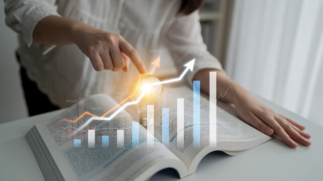 A businessperson analyzes financial data represented by graphs and trends overlaid on an open book in a bright, modern office. Insightful visual analysis concept. Scalp - Powered by Adobe