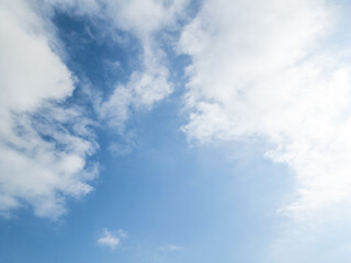 Bright Blue Sky Dominated by Fluffy White Cumulus and Cirrus Clouds with Strong Sunlight on the Right