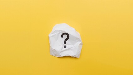 White Crumpled Paper with a Dark Question Mark on a Plain Yellow Surface.