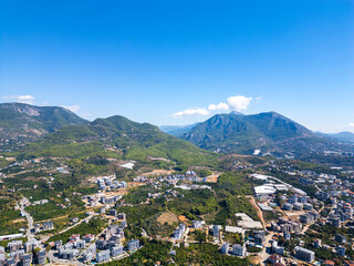 Scenic Drone Shot of a Mediterranean Mountain Pass, Revealing a Mix of Urban Development, Farmland, and Dense Forest on a Cloudy Day