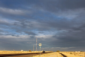 US Route 90 with dark clouds and brown grass in Marfa, Texas