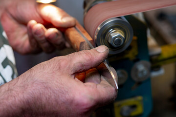 A close-up of a craftsman's hands as he creates a hunting knife.