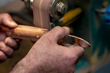 A close-up of a craftsman's hands as he creates a hunting knife.