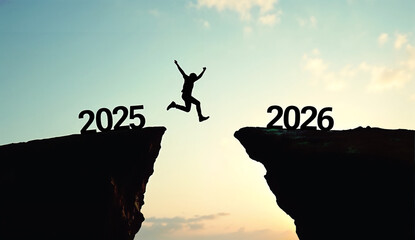 Silhouette Man jumping from 2025 cliff to 2026 cliff on sky background
