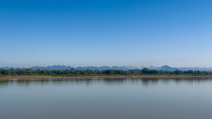 Scenic view of river with mountains against clear blue sky
