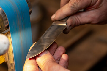 A close-up of a craftsman's hands as he creates a hunting knife.