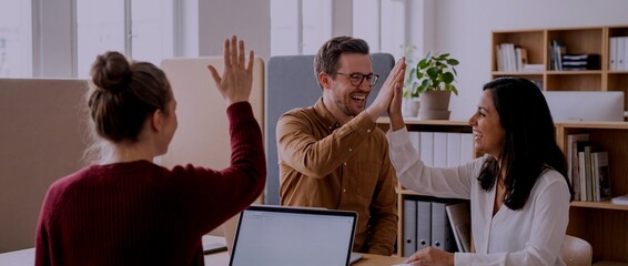 Team members share high fives during a meeting in a modern office