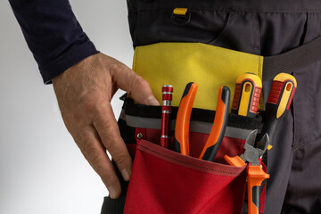 Electrician with tool belt with various instruments. Electrician worker at work.