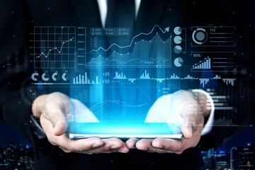 Businessman in Suit Holding Digital Tablet with Financial Data Graphics and Analytics Overlays in Modern Urban Setting at Night Scalp.