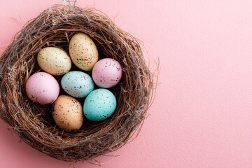 Obraz premium colorful speckled eggs resting in a natural twig nest on a soft pink background