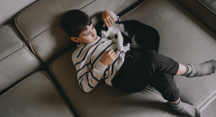 Child cuddles feline, Young boy snuggling with pet cat in cozy room scene