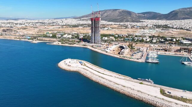 Aerial drone cinematic video of iconic project in development called "The Ellinikon" in coastal waterfornt of glyfada featuring Riviera Tower, Park, Marina and mall facilities, Attica, Greece