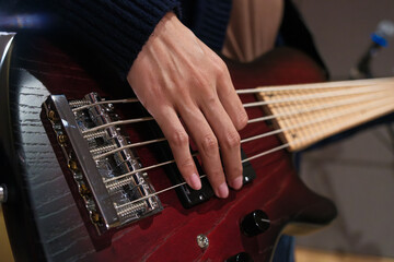 Close up female musician playing bass guitar at music studio. Positive musician girl enjoy instrumental music. Skill and practice, enjoyment and relax, entertainment and lifestyle.