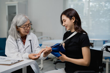 Obraz premium Doctor checking injured hand of patient with arm sling