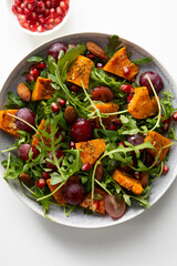 Fresh salad with roasted pumpkin and grapes on plate  top view