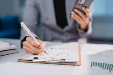 Businesswoman analyzing financial data and charts using smartphone