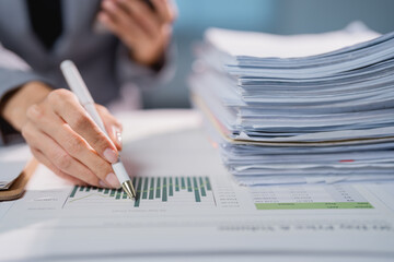 Business person analyzing financial data and piles of paperwork