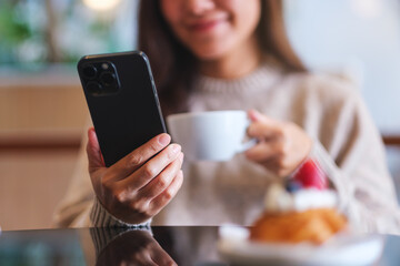 Closeup of a woman holding and using mobile phone in cafe