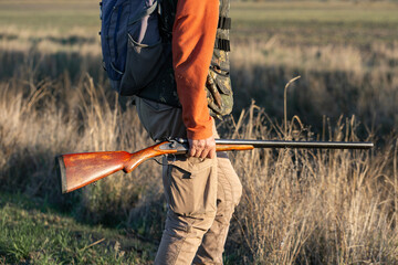 A hunter with a gun in camouflage clothing. A gentleman with a gun, medium shot, unrecognizable.
