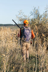 A hunter with a gun in camouflage clothing. A gentleman with a gun, medium shot, unrecognizable.