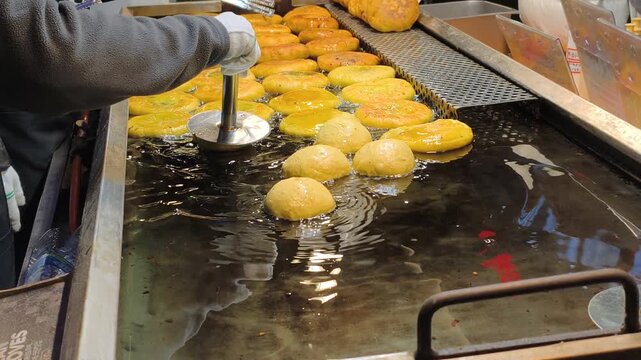Focus on precise deep frying process. Golden yellow sweets submerged in oil, showcasing culinary arts. Deep frying process achieves perfect crunch. Culinary arts skill evident.