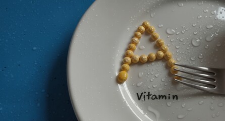 vitamin supplement pills forming the word ?�?vitamin' on a wet white plate with a silver fork.