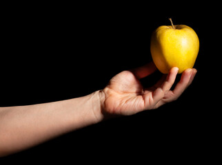 yellow apple in hand on black background