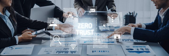 A professional business meeting focuses on cybersecurity strategy with a visual representation of the Zero Trust concept, showcasing teamwork and modern technology in an office. Trope
